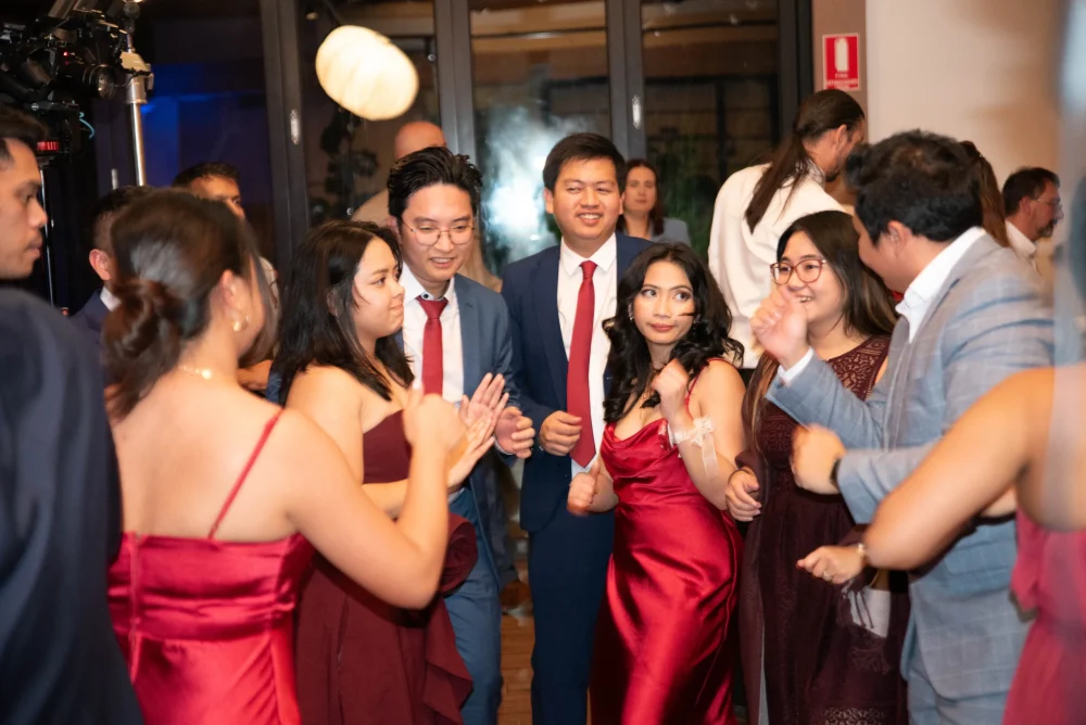 A diverse group of happy guests dancing at a lively wedding reception, with a personalized banner in the background. Photographed by Matt Jefferies Entertainment.