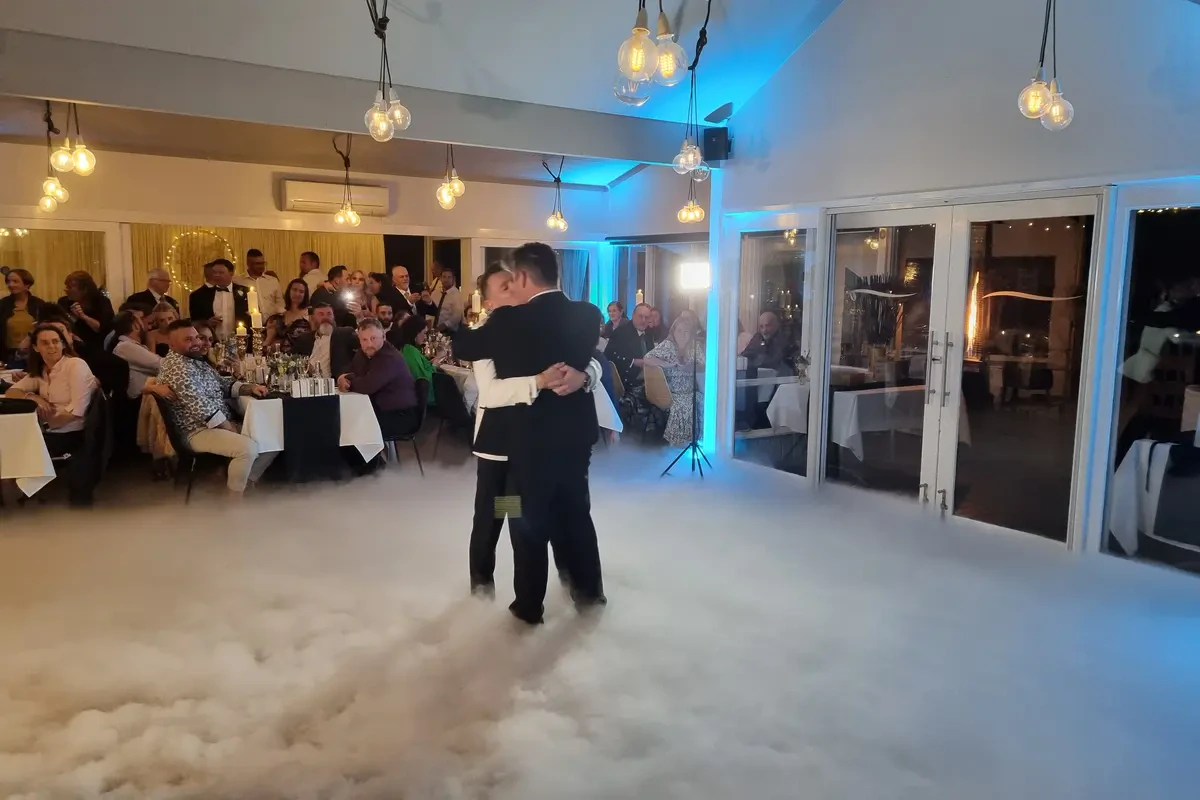 Newlyweds enjoying an elegant first dance enveloped in a heavy floor fog dry ice cloud effect during a Melbourne wedding reception.