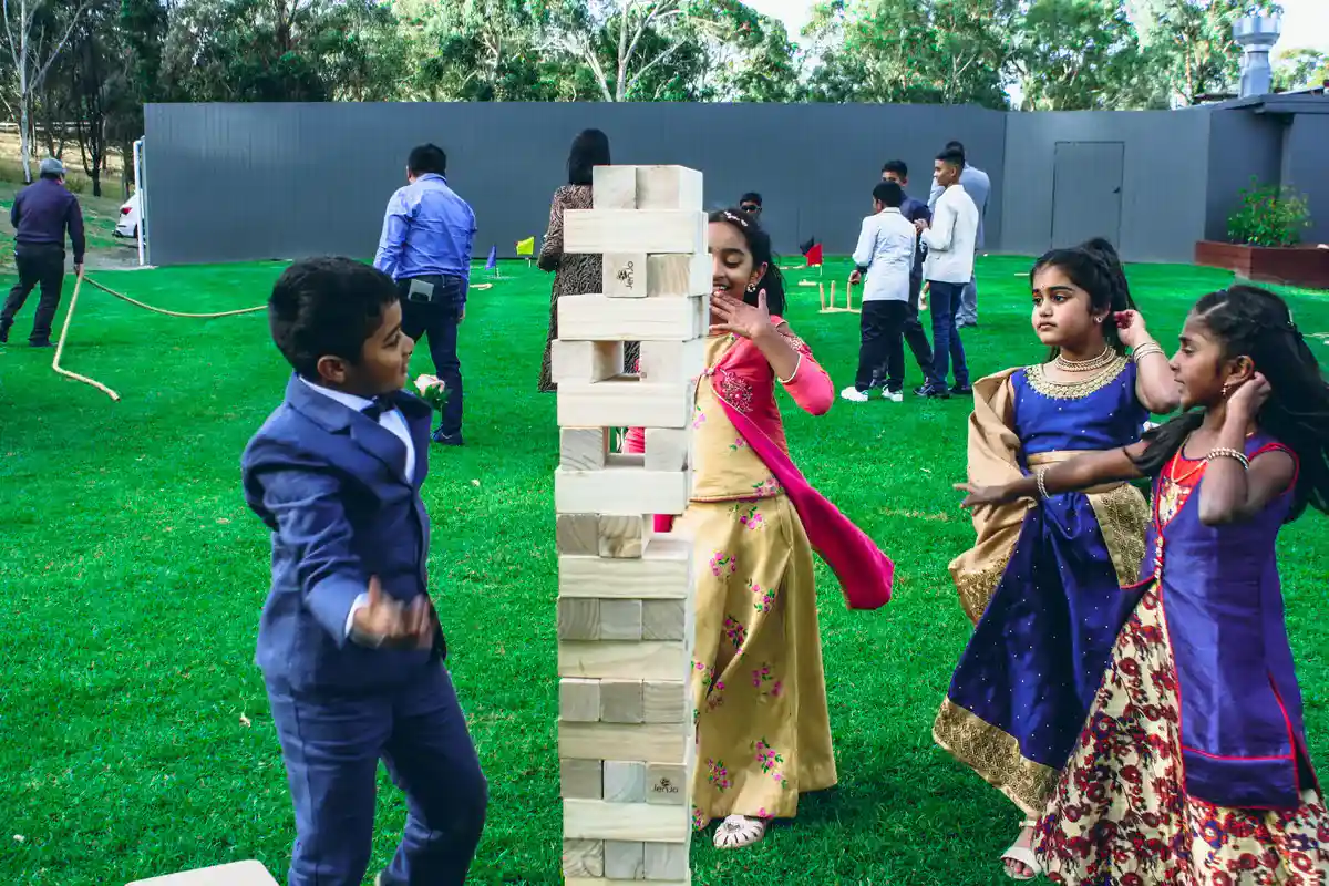 Wedding guests playing giant Jenga lawn games during cocktail hour on the grounds at Bramleigh Estate.